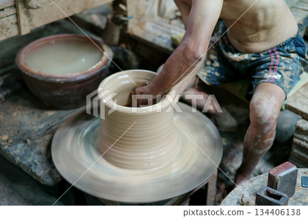Selective focus on the clay work on the spinning tray with hands of worker Selective focus on the clay work on the spinning tray with hands of worker 134406138
