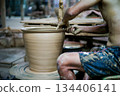 The skilled worker doing the clay work on the spinning wheel for modeling the shape of jar. 134406141