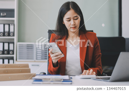 Asian business woman working on a laptop in a professional office Asian business woman working on a laptop in a professional office 134407015