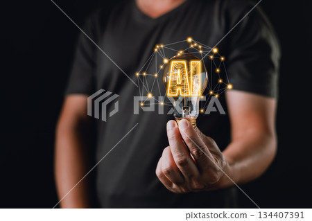 A person holds a glowing lightbulb with digital connections and the text AI inside, symbolizing idea, innovation, and creative technology powered by artificial intelligence and neural networks. 134407391
