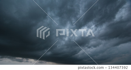 A dense, dark sky filled with swirling storm clouds signals an intense windstorm, emphasizing the power and drama of nature's environment in turbulent weather conditions. 134407392