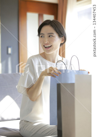 一位女士打開購物袋，臉上露出笑容。 134407453
