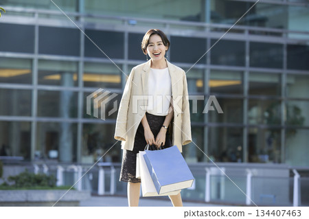 一位女士在城市裡漫步,享受購物的樂趣。 一位女士在城市裡漫步,享受購物的樂趣。 134407463