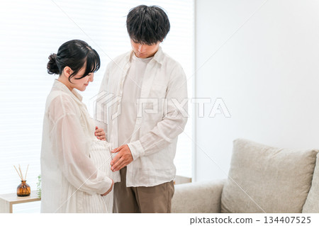 A couple in the living room of their home, a pregnant woman (maternity) 134407525