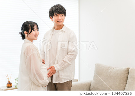 A couple in the living room of their home, a pregnant woman (maternity) A couple in the living room of their home, a pregnant woman (maternity) 134407526