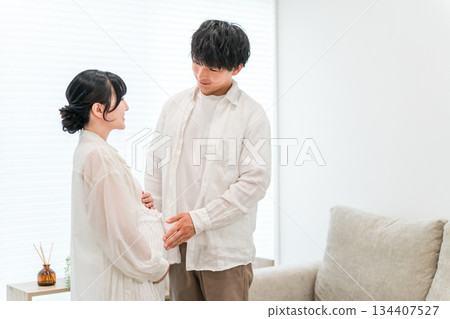 A couple in the living room of their home, a pregnant woman (maternity) 134407527