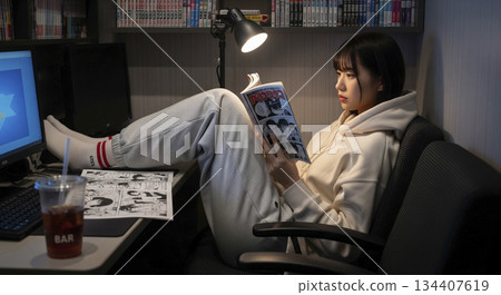 一位女士在漫畫咖啡館的私人包廂裡看漫畫 134407619