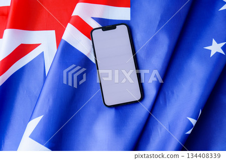 Smartphone with empty white screen on background of Australian flag. Mock up template copy space for custom copy designs. Place your logo or text on the white screen phone Smartphone with empty white screen on background of Australian flag. Mock up template copy space for custom copy designs. Place your logo or text on the white screen phone 134408339