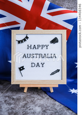 Letterboard with text HAPPY AUSTRALIA DAY next to the Aussie flag festive greeting cards. Australian flag. Concept of joy and national spirit 134408346