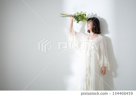 一位年輕女子手捧花束,在白色背景下展現出自然的笑容和清澈的氣質。圖片可用於婚紗照、植物攝影等。 一位年輕女子手捧花束,在白色背景下展現出自然的笑容和清澈的氣質。圖片可用於婚紗照、植物攝影等。 134408459