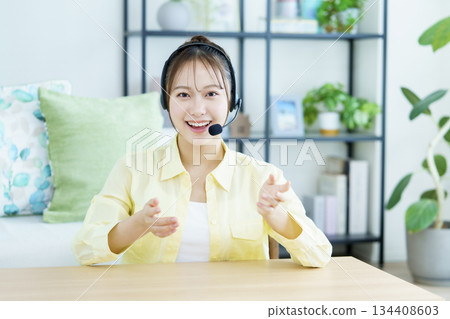 Young Japanese women wearing headsets and having a conversation in the living room Young Japanese women wearing headsets and having a conversation in the living room 134408603