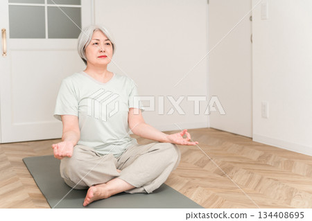 Senior woman doing yoga on a yoga mat at home 134408695