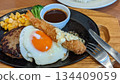 Hamburger steak topped with a fried egg and fried shrimp 134409059