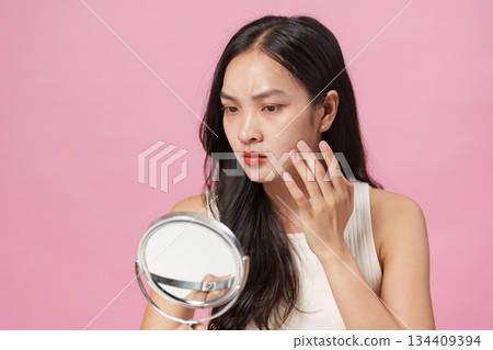 Skincare Check. Woman examining skin in mirror for beauty routine. Skincare Check. Woman examining skin in mirror for beauty routine. 134409394