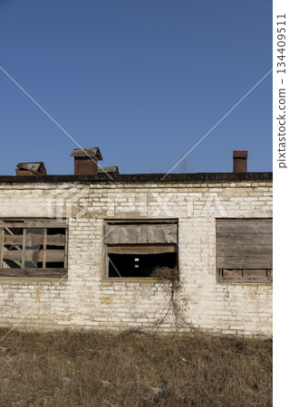 abandoned building in the winter, an abandoned building intended for demolition, the entrances and windows to the building are boarded up 134409511