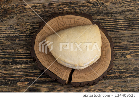 fresh shortbread bun with cottage cheese filling on a wooden board on the table, soft pastries stuffed with cottage cheese and sugar are on the board 134409525