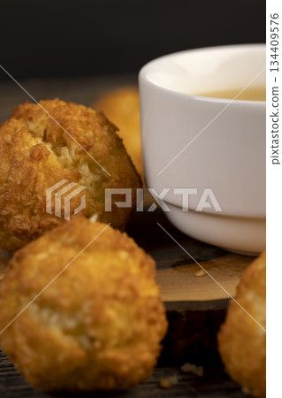 sweet cookies with coconut pieces are on the table, a group of sweet freshly made cookies for a tea party, a white cup filled with hot tea sweet cookies with coconut pieces are on the table, a group of sweet freshly made cookies for a tea party, a white cup filled with hot tea 134409576