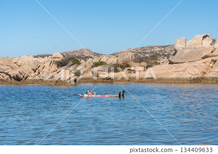 People floating on calm sea water near rocky coast on a sunny day. Summer leisure, seaside vacation and peaceful coastal atmosphere, Sardinian, La Maddalena, Italy People floating on calm sea water near rocky coast on a sunny day. Summer leisure, seaside vacation and peaceful coastal atmosphere, Sardinian, La Maddalena, Italy 134409633