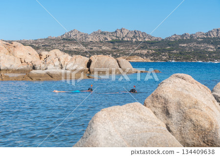 People swimming in the sea near a rocky coastline on a sunny summer day. Leisure activity, seaside vacation and natural coastal environment, Sardinian, La Maddalena, Italy People swimming in the sea near a rocky coastline on a sunny summer day. Leisure activity, seaside vacation and natural coastal environment, Sardinian, La Maddalena, Italy 134409638