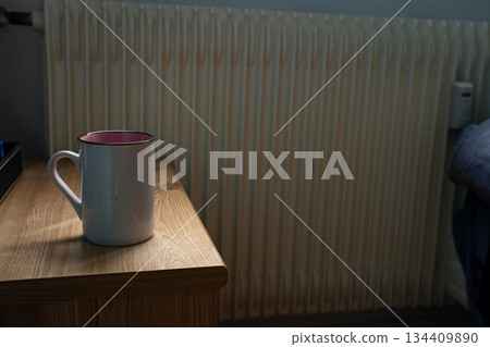 Backlit coffee cup standing on bedside table Backlit coffee cup standing on bedside table 134409890