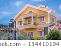 Exterior of a yellow two-storey house with classical facade and front garden 134410194
