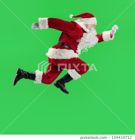 Santa Claus runs quickly against a green background during the holiday season for a festive event focused on fun and joy 134410712