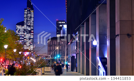 Warsaw, Poland. 4 November 2025. People walk along the sidewalks in the vicinity of large shop windows after dark. Lights street and buildings towering around them. Nearby with cars passing. Warsaw, Poland. 4 November 2025. People walk along the sidewalks in the vicinity of large shop windows after dark. Lights street and buildings towering around them. Nearby with cars passing. 134411853