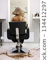Rear view of woman with freshly right sleek bob haircut sits in chair, cut hair on floor in beauty salon. Clean lines and even length of the cut highlight. Concept of professional hairstylists work 134412297