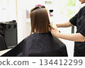 Unrecognisable hairdresser cutting female client hair with professional barber scissors and comb and making stylish haircut short bob hairstyle in beauty salon. Hair care, hair salon and hairstyling 134412299