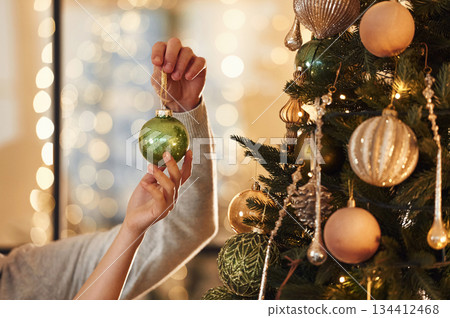 Close up view of man's and woman's hands that are holding New Year decoration for the tree Close up view of man's and woman's hands that are holding New Year decoration for the tree 134412468