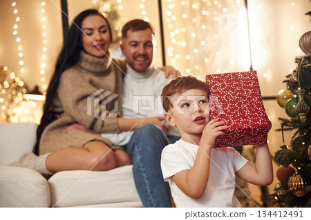 Child is with red gift box. Happy family celebrating new year together at home Child is with red gift box. Happy family celebrating new year together at home 134412491