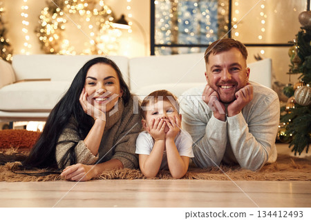 Laying down on the floor, smiling. Happy family celebrating new year together at home Laying down on the floor, smiling. Happy family celebrating new year together at home 134412493