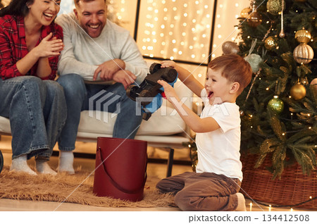 Happy boy is with gift. Family celebrating new year together at home 134412508
