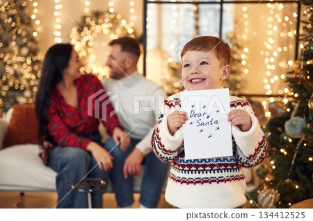 Boy is holding letter for Santa. Happy family celebrating new year together at home 134412525