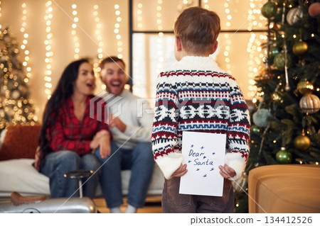 Boy is holding letter for Santa. Happy family celebrating new year together at home 134412526