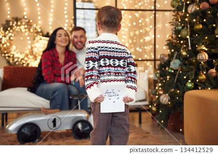 Dear Santa, boy is holding letter. Happy family celebrating new year together at home Dear Santa, boy is holding letter. Happy family celebrating new year together at home 134412529