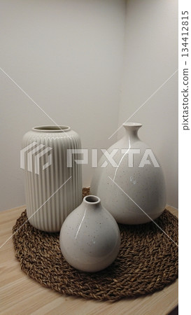 Minimalist ceramic vases arranged on natural woven mat Minimalist ceramic vases arranged on natural woven mat 134412815