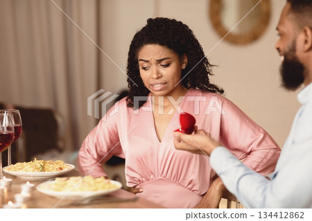 Breakup Concept. Black guy making marriage proposal to unsure woman thinking how to reject offer, frustrated girlfriend don't want to marry her boyfriend, not taking engagement ring, thinking 134412862