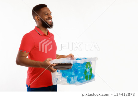 Recycle And Sort Your Waste. Side View Of Black Guy Holding Box With Recycling Sign Full Of Used Plastic Litter And Bottles Posing In Studio On White Background. Free Space For Text Recycle And Sort Your Waste. Side View Of Black Guy Holding Box With Recycling Sign Full Of Used Plastic Litter And Bottles Posing In Studio On White Background. Free Space For Text 134412878