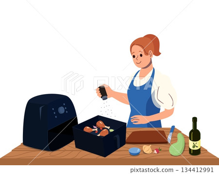 Smiling woman seasoning chicken drumsticks for cooking in modern air fryer at kitchen table with fresh vegetables and oil bottle healthy home meal 134412991