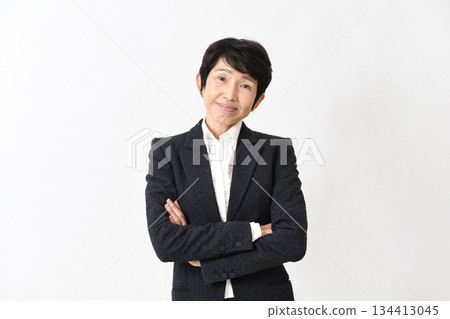 A smiling middle-aged woman in a suit with her arms crossed A smiling middle-aged woman in a suit with her arms crossed 134413045