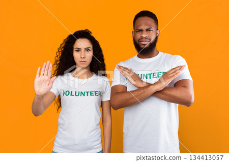 Stop It. Two Multicultural Volunteers Female And Male Gesturing Stop And Crossing Hands Looking At Camera Forbidding Something Standing Over Yellow Background. Studio Shot 134413057