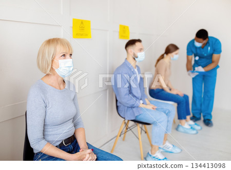 Senior woman and other patients waiting for covid-19 vaccine injection at hospital, consulting doctor, free space. Coronavirus medicine, treatment and population immunization concept 134413098