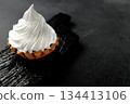 A sand basket with protein cream stands on a black wooden board on a gray background 134413106