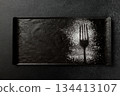 Imprint of a fork with powdered sugar on a black rectangular plate 134413107