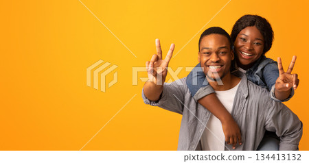 Portrait Of Cheerful Black Lovers Having Fun, Embracing And Showing Peace Gestures At Camera, Young Positive African American Couple Fooling Over Yellow Background, Enjoying Spending Time Together Portrait Of Cheerful Black Lovers Having Fun, Embracing And Showing Peace Gestures At Camera, Young Positive African American Couple Fooling Over Yellow Background, Enjoying Spending Time Together 134413132