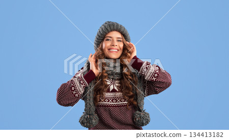 Portrait of pretty lady wearing fashionable knitted winter clothes on blue background Portrait of pretty lady wearing fashionable knitted winter clothes on blue background 134413182