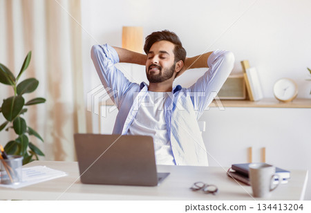 Successful Working Day. Handsome Arab Businessman Leaning Back In Chair At Office With Hands Behind Back, Glad Middle Eastern Male Entrepreneur Relaxing At Desk On Workplace, Free Space 134413204