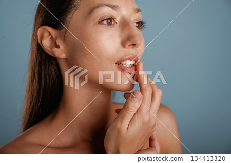 Smooth clean skin, posing. Young woman is in the studio against background 134413320