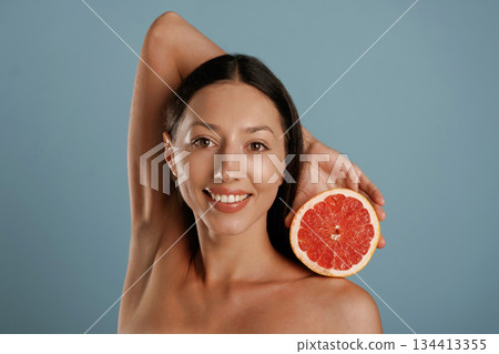Grapefruit, conception of healthy eating. Young woman is in the studio against background Grapefruit, conception of healthy eating. Young woman is in the studio against background 134413355